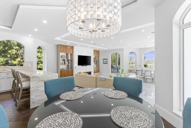 dining room with an inviting chandelier, a tray ceiling, wood finished floors, and recessed lighting