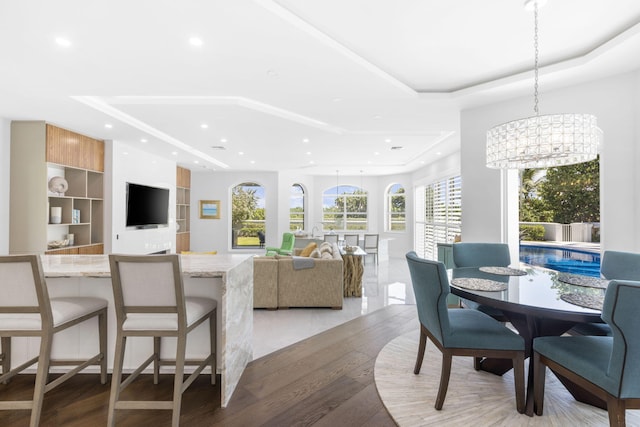 dining space with light wood finished floors, recessed lighting, a tray ceiling, and an inviting chandelier