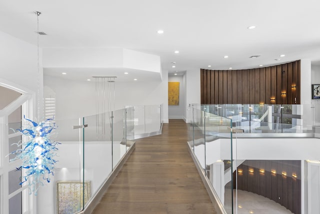 corridor with baseboards, wood finished floors, and recessed lighting