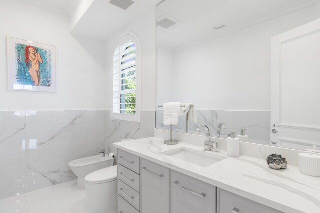 bathroom with a bidet, vanity, toilet, and tile walls