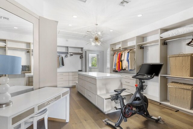 spacious closet featuring an inviting chandelier and hardwood / wood-style flooring