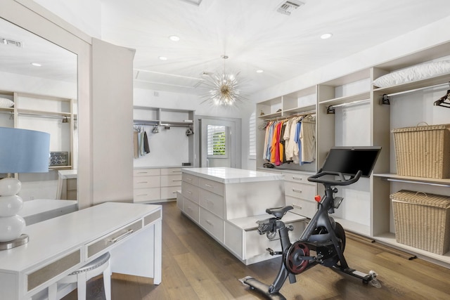 walk in closet with a chandelier, wood finished floors, and visible vents