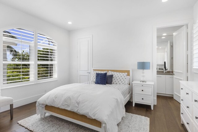 bedroom with ensuite bath, dark hardwood / wood-style flooring, and sink