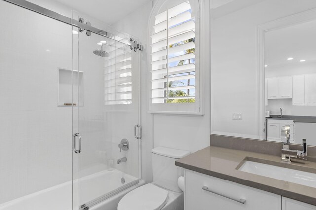 full bathroom featuring vanity, toilet, and bath / shower combo with glass door