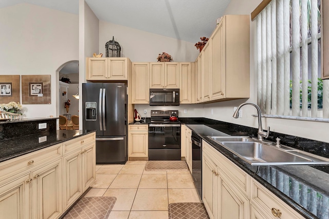 kitchen with light tile patterned floors, sink, black appliances, dark stone counters, and cream cabinetry