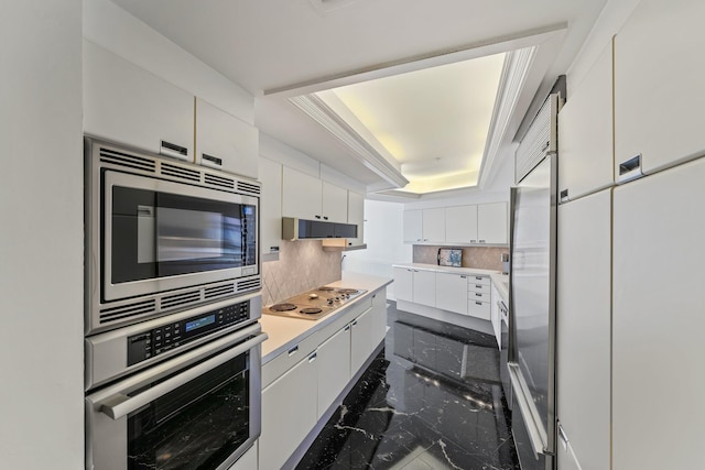 100 Lakeshore Dr Unit 457, North Palm Beach, FL 33408 - kitchen with built in appliances, a tray ceiling, white cabinetry, tasteful backsplash, and dark marble finish floors