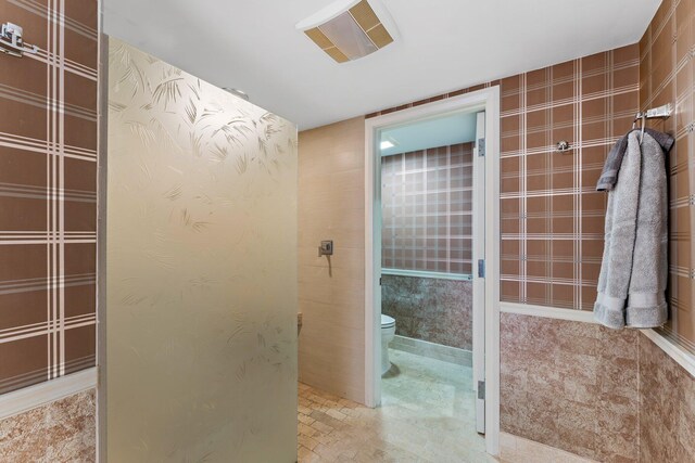 washroom with cabinets, stacked washing maching and dryer, electric water heater, and sink