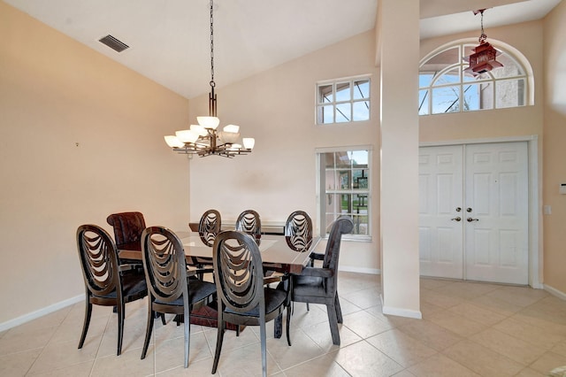 tiled dining space featuring an inviting chandelier and high vaulted ceiling