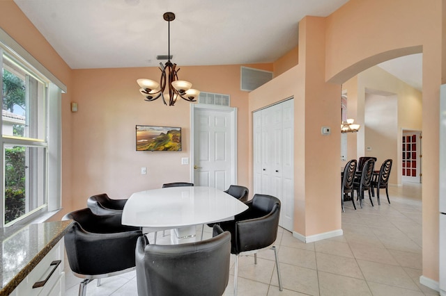 dining room featuring a chandelier, light tile patterned floors, and vaulted ceiling