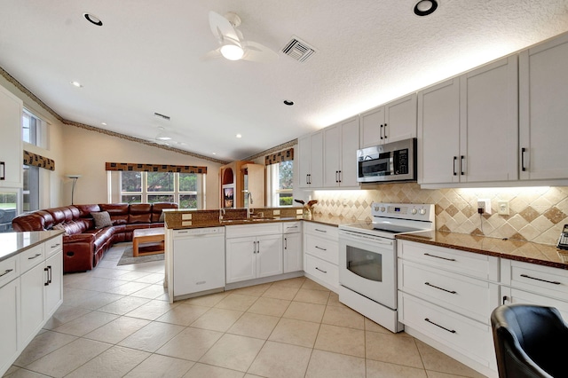 kitchen with lofted ceiling, white cabinetry, a textured ceiling, sink, and white appliances