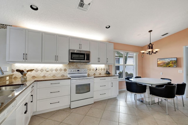 kitchen featuring vaulted ceiling, white cabinets, hanging light fixtures, and white appliances