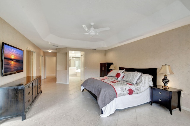 tiled bedroom featuring a raised ceiling, ceiling fan, and ensuite bath