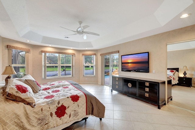 bedroom featuring access to exterior, light tile patterned floors, a tray ceiling, and ceiling fan