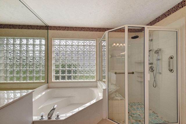 bathroom featuring a textured ceiling and shower with separate bathtub