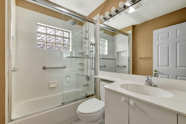 full bathroom featuring vanity, toilet, and shower / bath combination with glass door