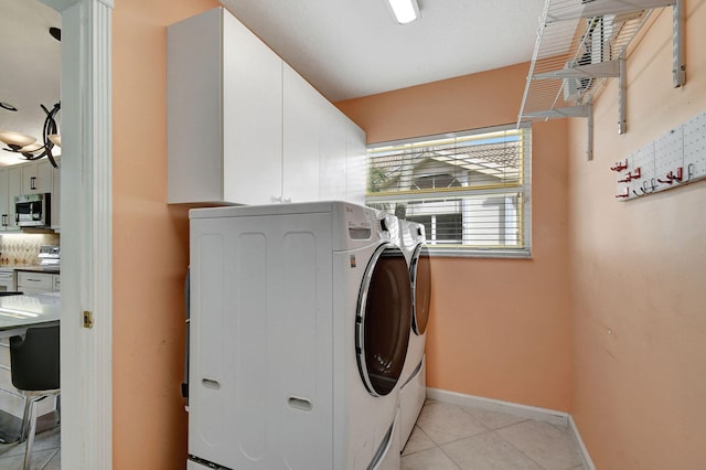 laundry area with cabinets, washer and clothes dryer, and light tile patterned floors