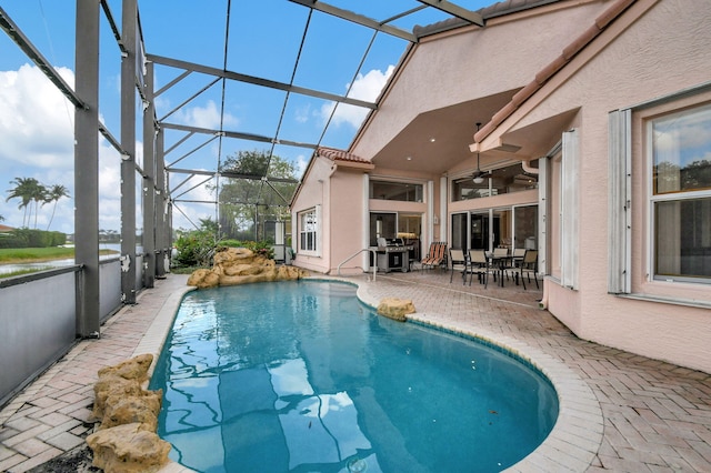 view of pool featuring a patio, ceiling fan, and glass enclosure