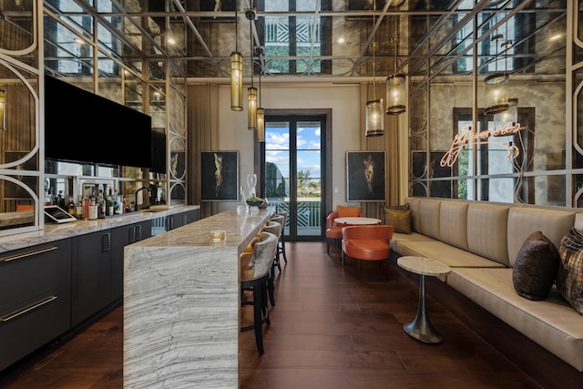 kitchen with a towering ceiling, light stone counters, and dark hardwood / wood-style floors