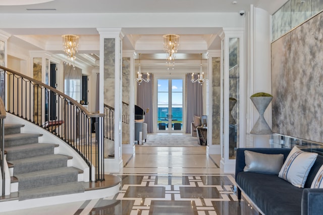 foyer entrance featuring a water view, an inviting chandelier, crown molding, and ornate columns