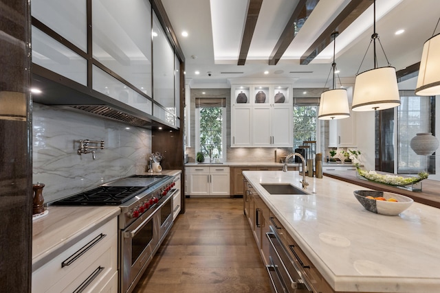 kitchen featuring beamed ceiling, range with two ovens, sink, dark wood-type flooring, and white cabinets