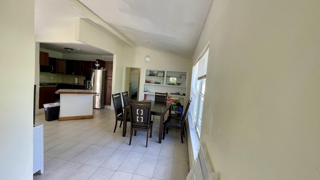 dining area featuring lofted ceiling and light tile patterned flooring