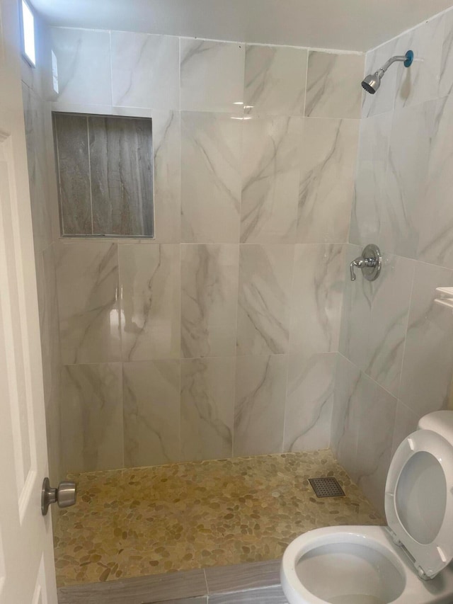 bathroom featuring toilet and tiled shower