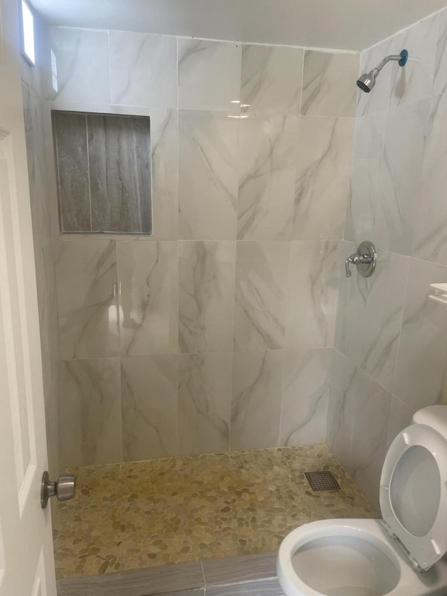 bathroom with toilet, visible vents, and tiled shower