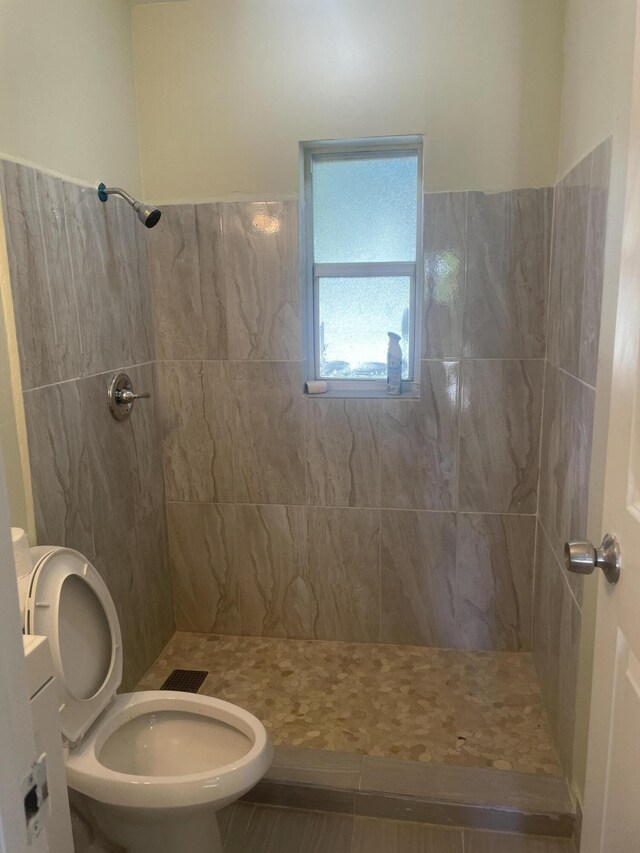 bathroom with tiled shower and toilet