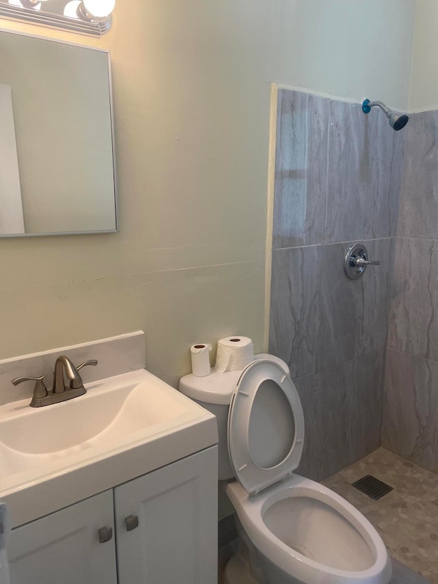 bathroom with tiled shower, toilet, and vanity