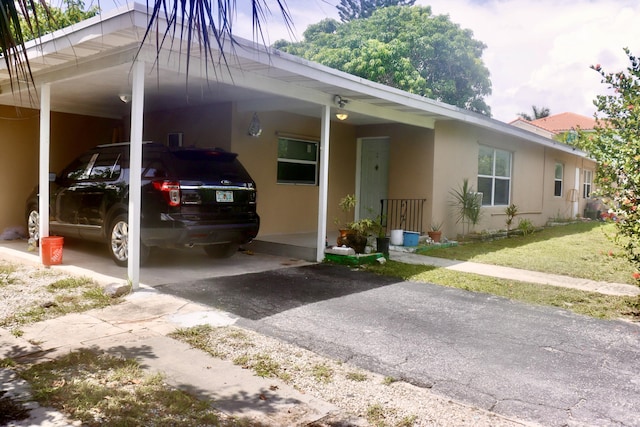 view of front of home featuring stucco siding, driveway, an attached carport, and a front yard