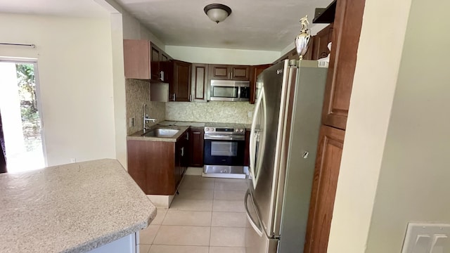 kitchen featuring tasteful backsplash, light countertops, light tile patterned floors, stainless steel appliances, and a sink