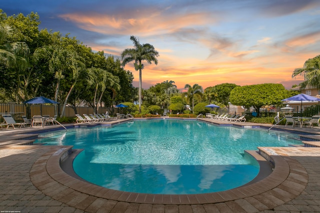 pool at dusk featuring a patio