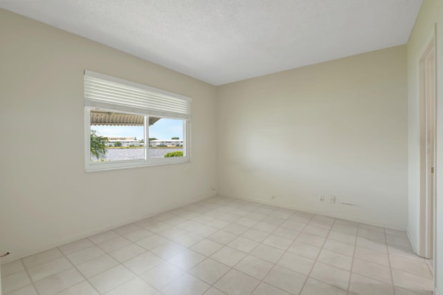 tiled spare room featuring a textured ceiling