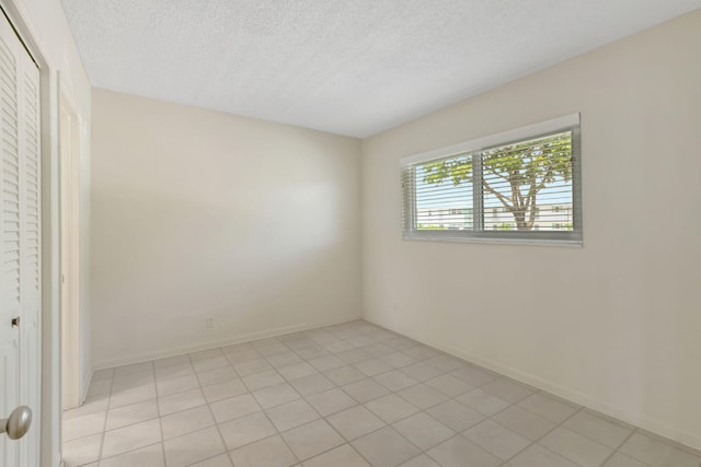 interior space featuring a textured ceiling, light tile patterned floors, and a closet