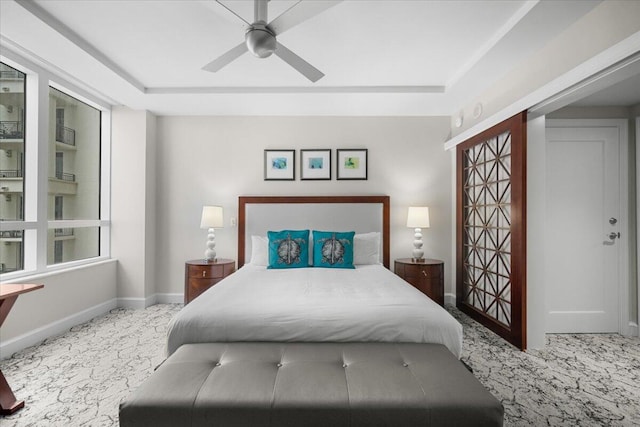 bedroom with ceiling fan, a tray ceiling, and carpet flooring