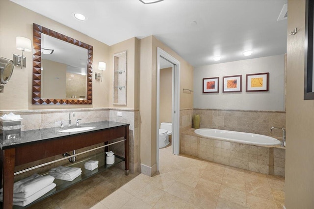 bathroom with tiled tub, toilet, tile patterned flooring, tasteful backsplash, and vanity