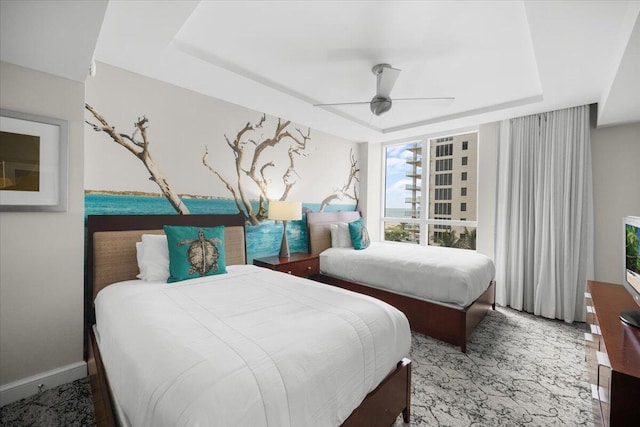 bedroom with ceiling fan and a raised ceiling