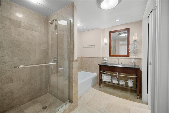 bathroom with tile walls, tile patterned flooring, separate shower and tub, and vanity