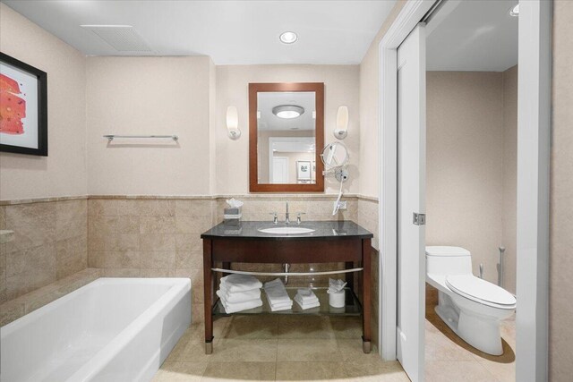 bathroom with tile patterned flooring, a tub, vanity, and toilet