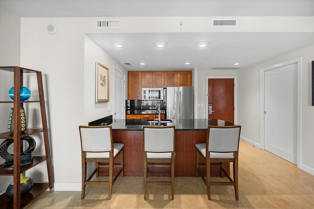 kitchen with backsplash, sink, high end fridge, a breakfast bar area, and light tile patterned flooring