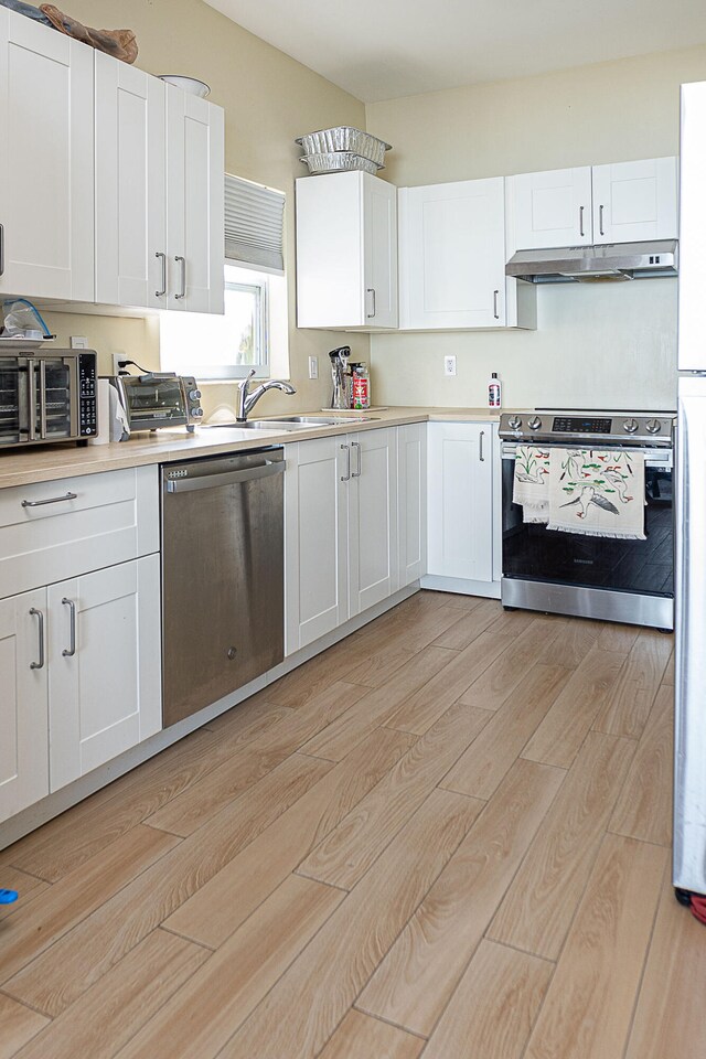 kitchen featuring white cabinets, stainless steel appliances, sink, and light hardwood / wood-style flooring