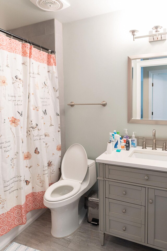 bathroom with walk in shower, wood-type flooring, vanity, and toilet