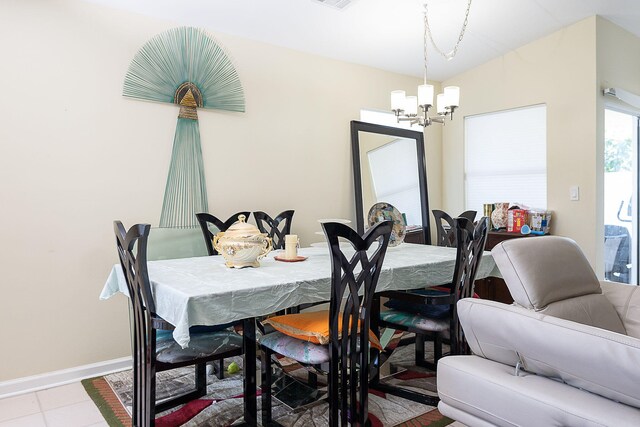 tiled dining room featuring an inviting chandelier and lofted ceiling