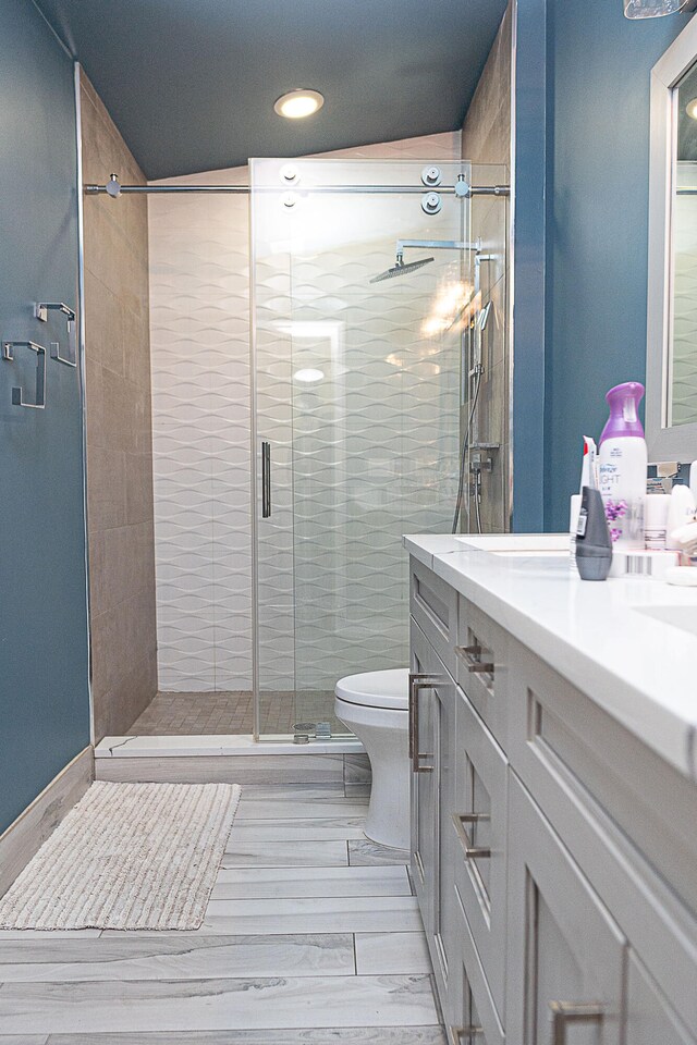 bathroom with hardwood / wood-style floors, walk in shower, vanity, and toilet