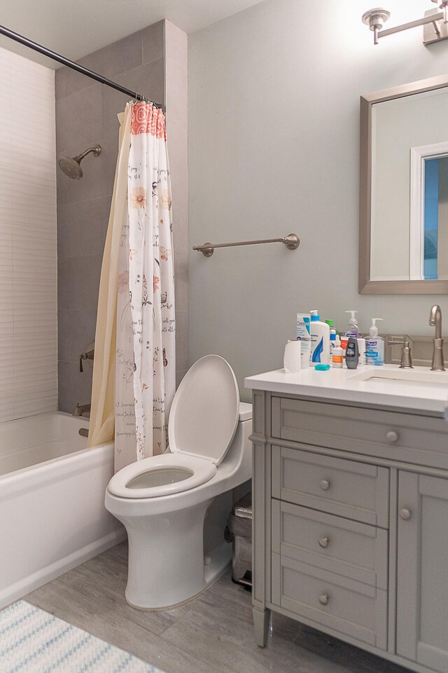 full bathroom with vanity, hardwood / wood-style flooring, shower / tub combo, and toilet