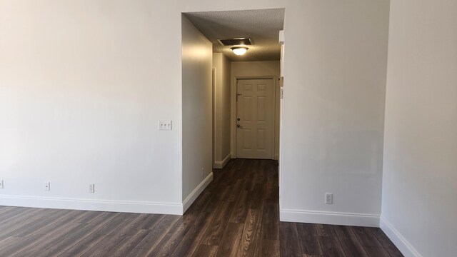 hall with a textured ceiling and dark wood-type flooring