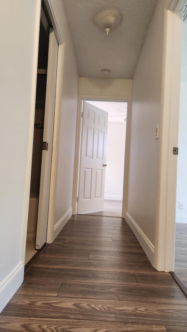 hallway with dark hardwood / wood-style flooring and a textured ceiling