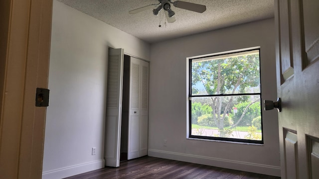 unfurnished bedroom with a textured ceiling, multiple windows, ceiling fan, and dark hardwood / wood-style floors