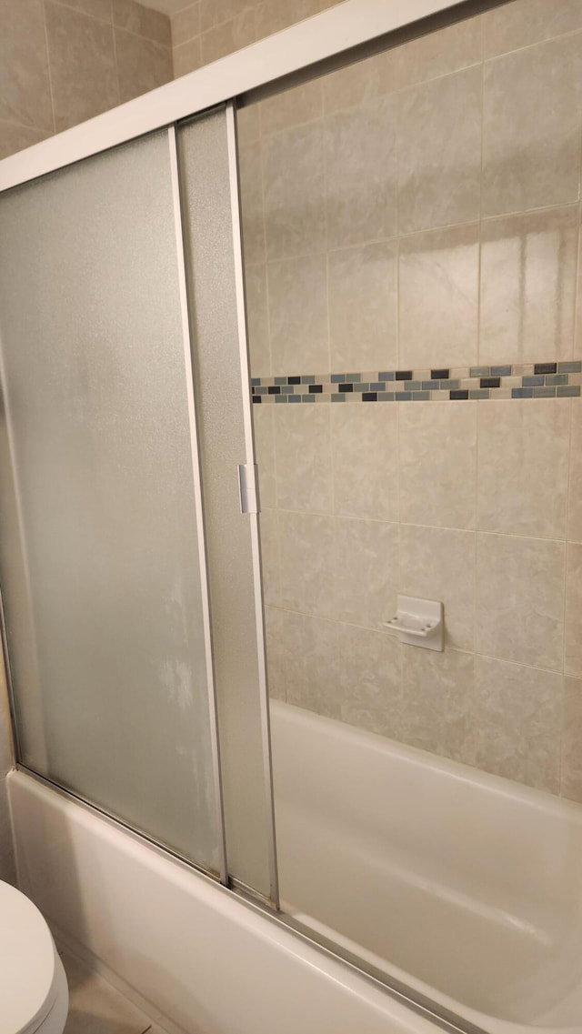 bathroom featuring shower / bath combination with glass door and toilet