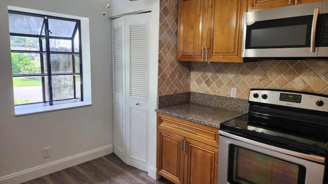 kitchen with dark hardwood / wood-style flooring, stainless steel appliances, tasteful backsplash, and dark stone counters